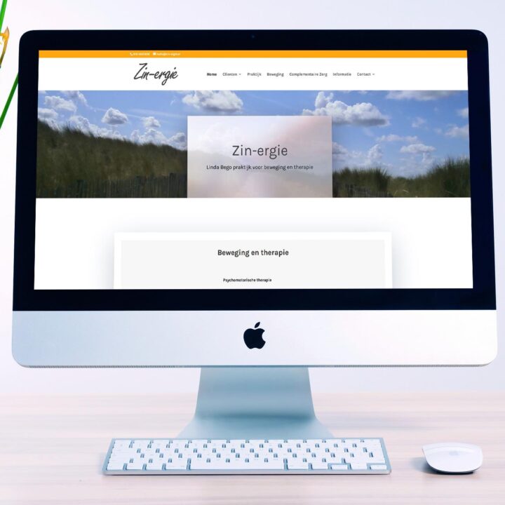 iMac on a light desk displaying a wellness website homepage with a navigation bar, hero image of blue sky and grass, and a translucent title card reading 'Zin-energie.' A potted plant sits to the left, with a white keyboard and mouse in front of the screen.